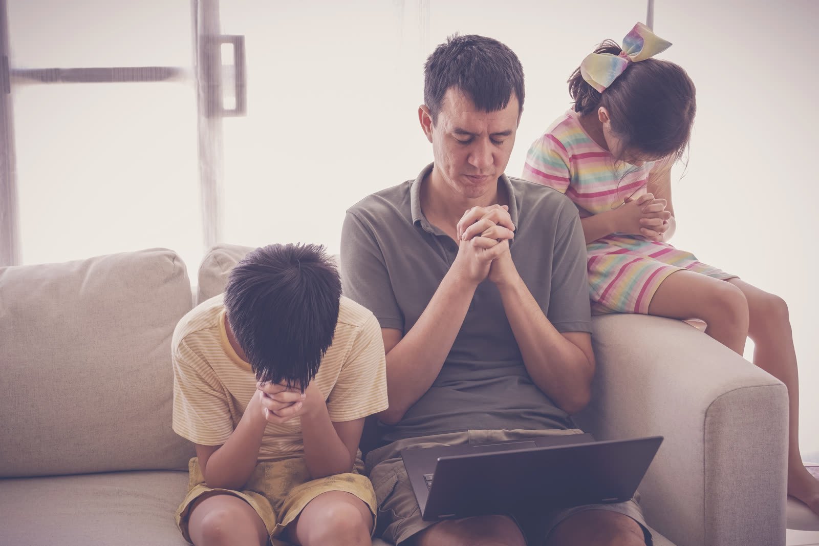 Un père prie avec ses enfants à la maison